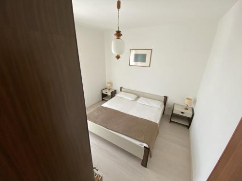 1 dormitorio pequeño con 1 cama y 2 mesas en Condominio Aquilone en Lignano Sabbiadoro
