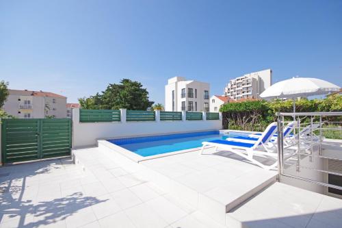 a swimming pool with a chair and an umbrella at Apartmani Srzic in Makarska