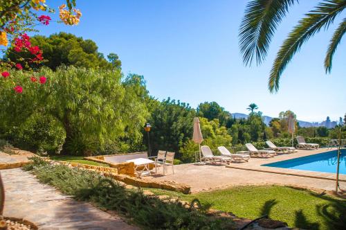 a pool with chaise lounge chairs and a palm tree at Villa Altozano with pool, barbeque, large garden, and fantastic sea views in Benidorm