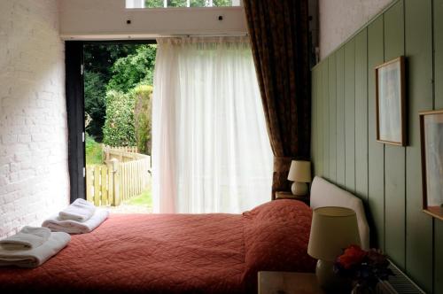 a bedroom with a red bed with a large window at Brackenborough Hall Coach House - Saddle Room in Louth