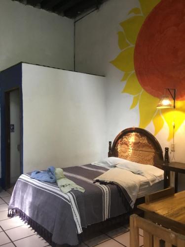 a bedroom with a bed in a room with a wall at Hostal Luz de Luna Nuyoo in Oaxaca City
