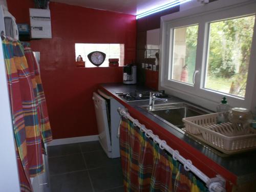 cocina con paredes rojas, lavabo y ventana en 2 Gîtes à Fleury les aubrais 1 studio ou 1 gîte, en Fleury-les-Aubrais