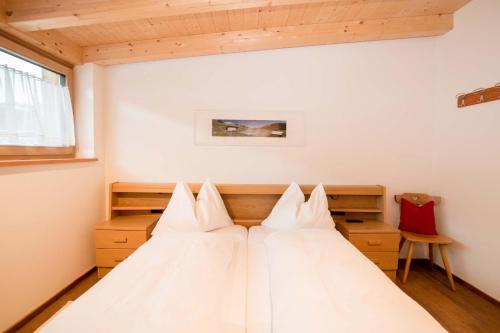 a bedroom with a bed with white pillows at App. Erta - Ciasa Lavarella in San Vigilio Di Marebbe