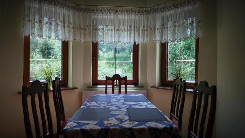 a dining room with a table and chairs and windows at Domek Leśna Przystań in Strękowizna