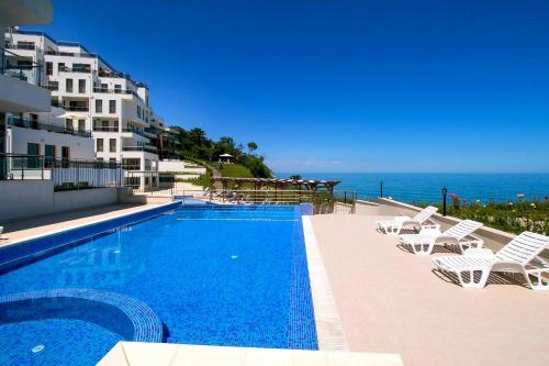 Una piscina con sillas y el océano al fondo. en Бяла Виста Клиф - Byala Vista Cliff, en Byala