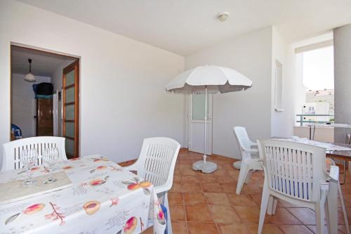 a dining room with a table and chairs and an umbrella at Apartmani Srzic in Makarska