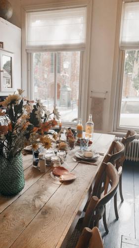 a wooden table with food on it in a room with windows at Logies De Reiziger in Groede