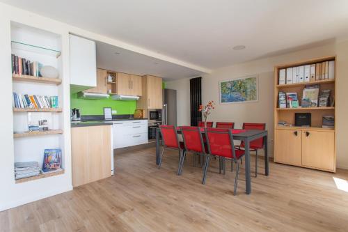 une cuisine et une salle à manger avec une table et des chaises rouges dans l'établissement LA PETITE PRESQU'ILE, à Locoal-Mendon