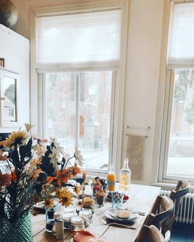 a dining room table with a vase of flowers on it at Logies De Reiziger in Groede