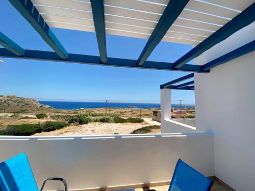 a view of the ocean from a house with blue chairs at Michail Suites Afiartis Karpathos in Karpathos Town