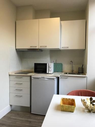 a kitchen with white cabinets and a table with a microwave at Romantic 1 Bedroom Apartment at Roma Avenue - 1C in Lisbon