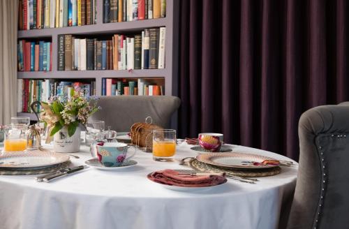Throphill Grange في موربيث: طاولة بيضاء مع أطباق من الطعام ورف كتاب مع كتب