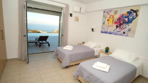a bedroom with two beds and a view of the ocean at Eva Villas East, with infinity pool & and panoramic sea view in Gerani