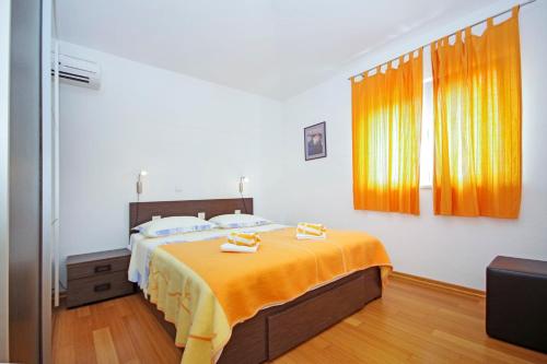 a bedroom with a bed with an orange blanket at Apartmani Srzic in Makarska
