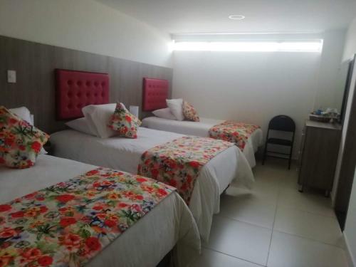 una habitación de hotel con 3 camas y una silla en Hotel Grato Manizales, en Manizales