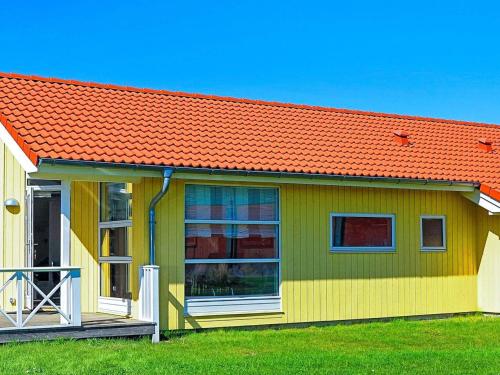 ein grünes und orangefarbenes Haus mit orangefarbenem Dach in der Unterkunft 8 person holiday home in Gro enbrode in Großenbrode