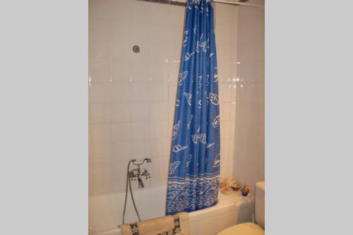 Baño con cortina de ducha azul junto a un aseo en Casa con Encanto en Pueblo Acantilado, en El Campello