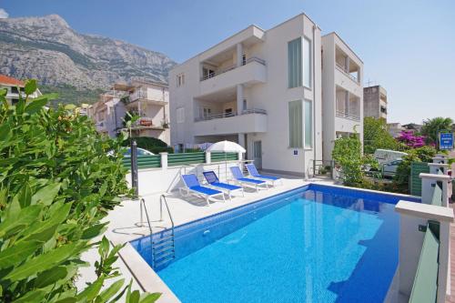 a villa with a swimming pool and a house at Apartmani Srzic in Makarska