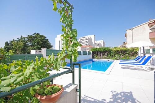 a patio with a swimming pool with a chair and plants at Apartmani Srzic in Makarska