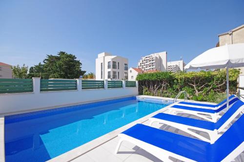 a swimming pool with two chairs and an umbrella at Apartmani Srzic in Makarska