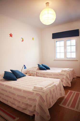 a bedroom with two beds with blue pillows on them at Casal Do Góis Guest House in Atouguia da Baleia