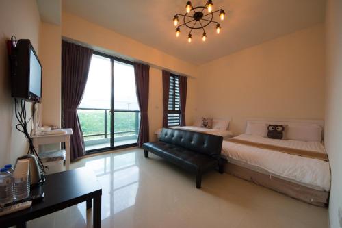 a bedroom with a bed and a couch and a chandelier at 七號會館 in Puli