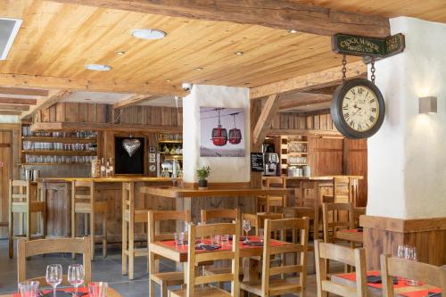 un restaurant avec des murs et des tables en bois et une horloge dans l'établissement Logis La Croix-Saint-Maurice, au Grand-Bornand