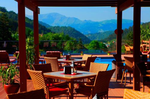 a patio with tables and chairs and a view of the mountains at Best Western Plus Paradise Hotel Dilijan in Dilijan