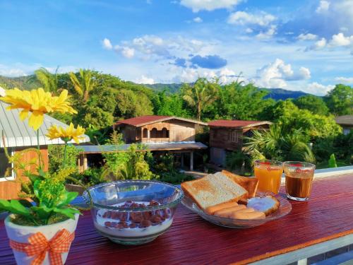 een houten tafel met eten en drinken op een balkon bij Mint Organic Farm Stay, Wangchin,Phrae in Ban Mae Katom