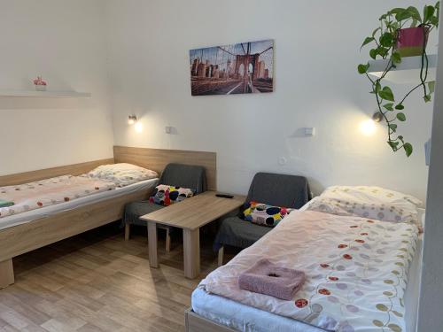 two beds in a room with chairs and a table at Penzion MAR in Hradec Králové