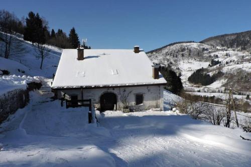 un bâtiment avec un toit enneigé dans la neige dans l'établissement Gite BUSSANG, à Bussang