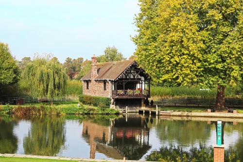 a small wooden house with a boat in the water at Shillingford Bridge Hotel in Wallingford