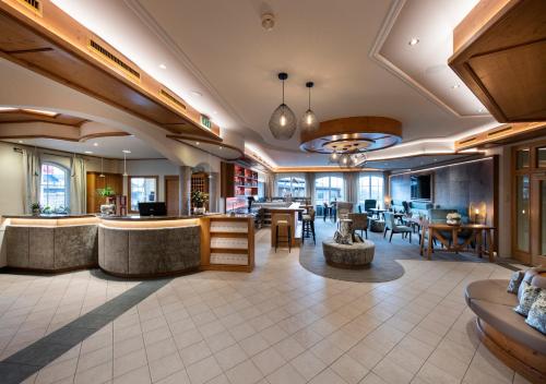 a lobby of a hotel with a bar and tables at Hotel Königgut in Wals