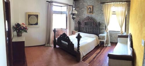 a bedroom with a large bed and a stone wall at O Pazo da Briona in Arzúa