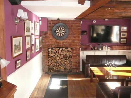 a living room with a fireplace and a clock on a wall at The Maidens Chambers in Canterbury