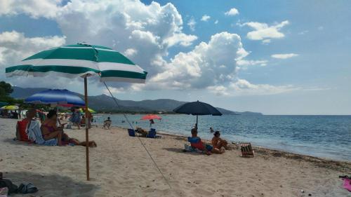 a group of people sitting on the beach under umbrellas at In front of the beach - La terrazza sul mare in Flumini di Quartu