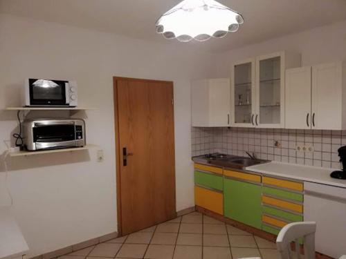 kuchnia z kolorowymi szafkami i drzwiami z kuchenką mikrofalową w obiekcie Ferienwohnung Kessel w mieście Appenheim