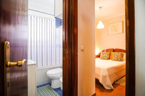 uma casa de banho com uma cama e um WC num quarto em Sol e Mar na Nazaré