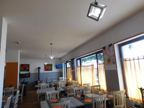 a dining room with white chairs and tables and windows at Albergo Alla Posta in Anduins