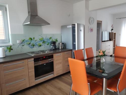 a kitchen with a glass table and orange chairs at Garden Baltic in Trzęsacz