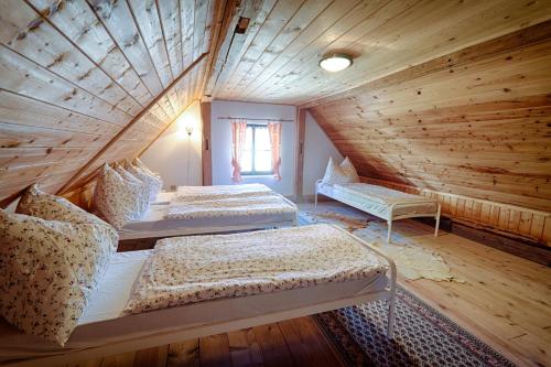 two beds in a room with a wooden ceiling at Chalupa Bozkovska in Vysoké nad Jizerou