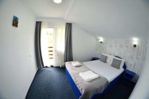 a bedroom with a white bed with a window at Pensiunea Casa Ady in Bran