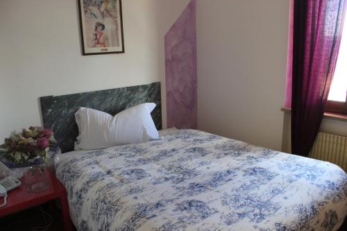 a bedroom with a bed with a blue and white comforter at Albergo Alla Posta in Anduins