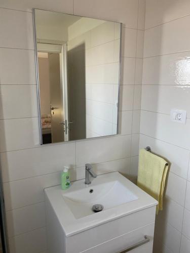 a white bathroom with a sink and a mirror at Apartmani Bella Vista in Njivice