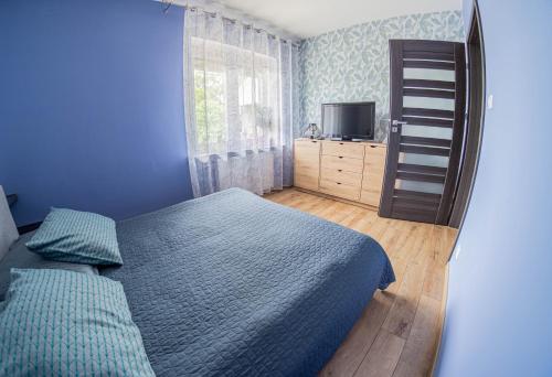 a blue bedroom with a bed and a television at Przestronny Apartament in Grzybowo