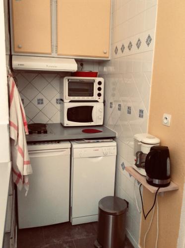une petite cuisine avec un micro-ondes et une cuisinière dans l'établissement Agréable appartement dans le vieux Trouville, à Trouville-sur-Mer