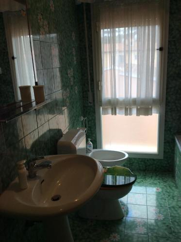 een badkamer met een wastafel, een toilet en een raam bij La Residenza in Porto Azzurro