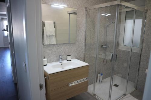 Un baño con lavabo y ducha de cristal. en FOROPLAZA Porta San Pedro Pleno Centro Vistas Muralla, en Lugo