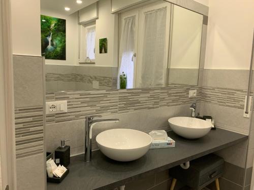 La salle de bains est pourvue de 2 lavabos et d'un miroir. dans l'établissement CEJM Apartments Merano, à Merano