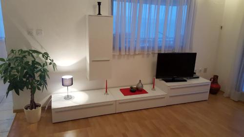 a living room with a tv on a white cabinet at Apartmani Antunović Podgora in Podgora